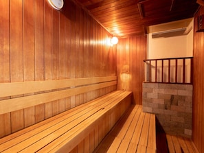 Una sauna de madera con bancos y una pared de piedra.