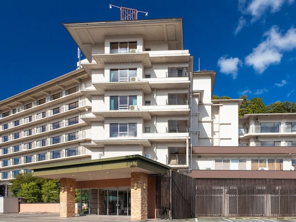 Un hotel de varios pisos con un diseño arquitectónico moderno, que cuenta con balcones, ventanas amplias y una entrada cubierta.