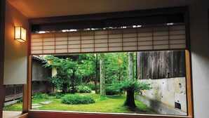 A traditional Japanese room with tatami flooring, a shoji screen, and a view of a lush garden. - Ooedo Onsen Monogatari Wanwan Resort Awazu (Komatsu)