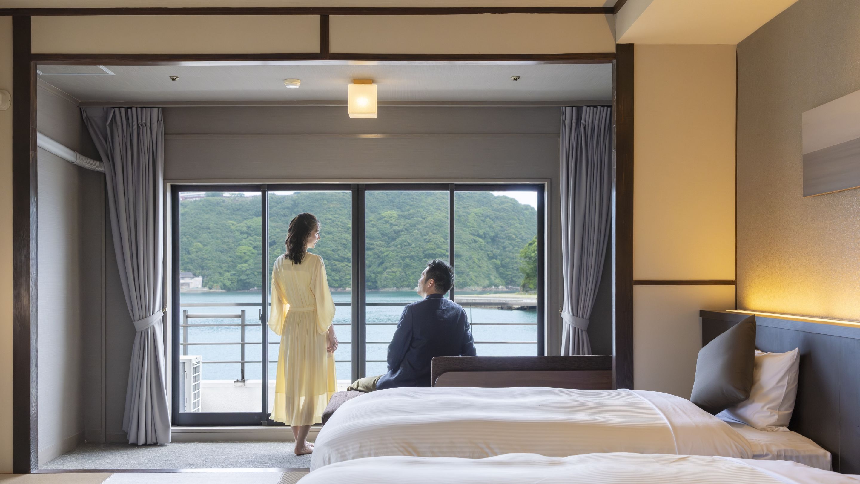 A hotel room with a large bed, a view of a body of water, and a balcony.