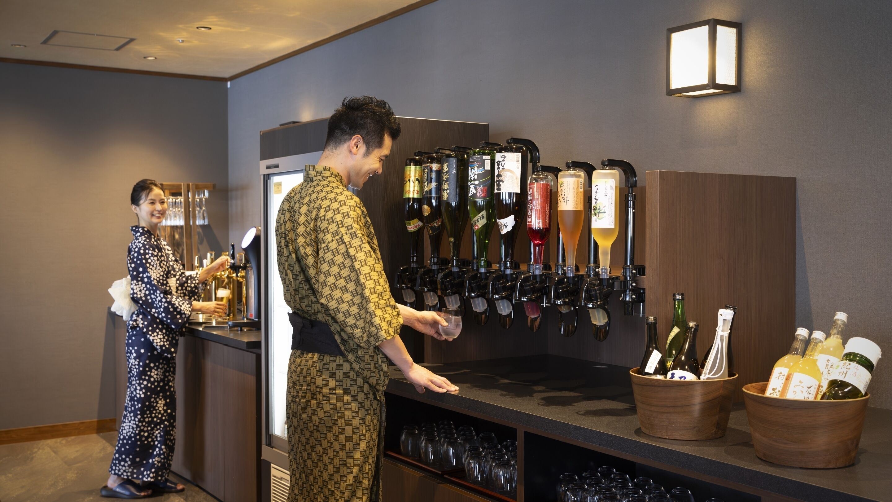 A bar area with multiple beer taps and bottles, a counter, and a person serving drinks.