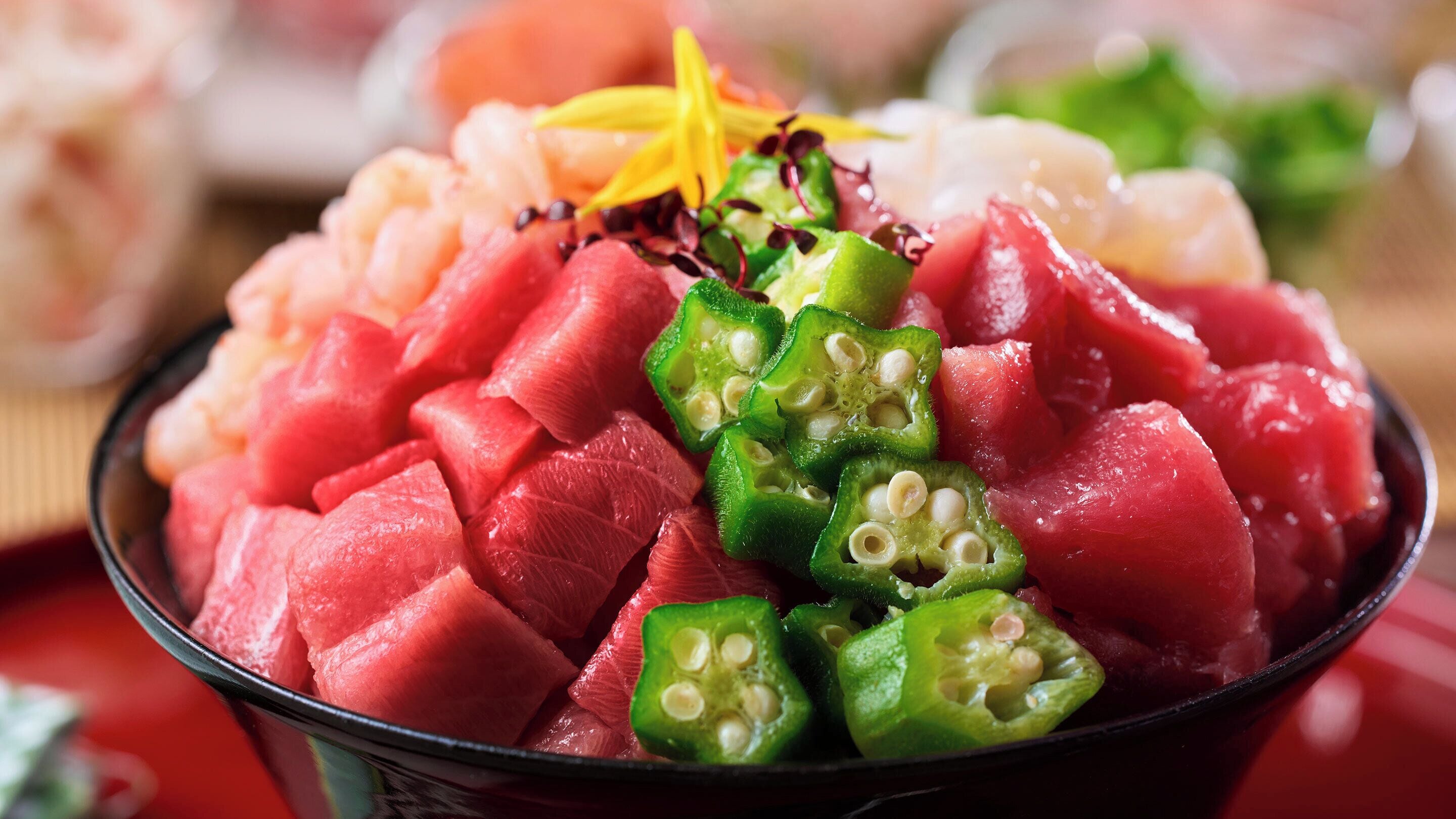 A bowl of sashimi with watermelon and green chili peppers.