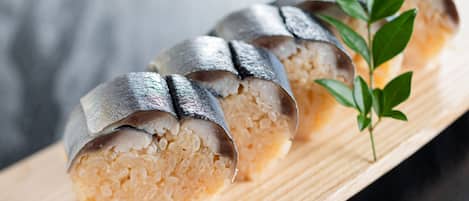 Ein Holzservierbrett mit Sushi-Rollen, belegt mit Fischscheiben.