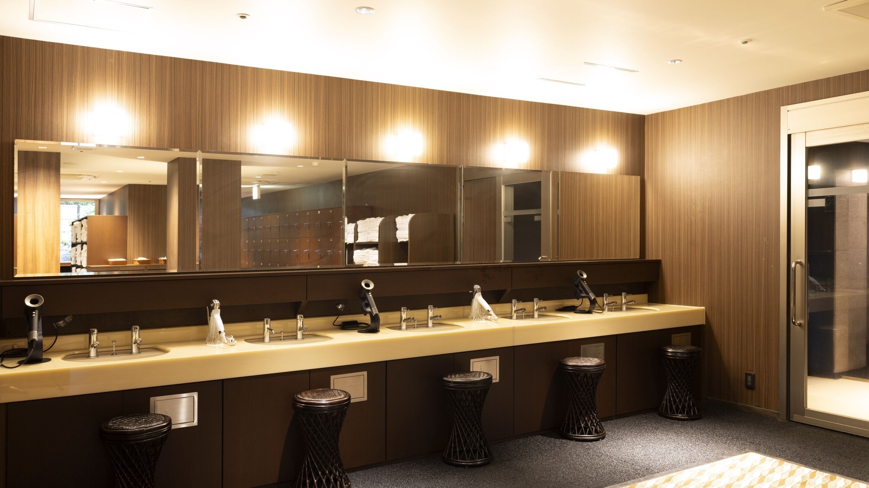 A modern bathroom with a long vanity, multiple sinks, and a large mirror.