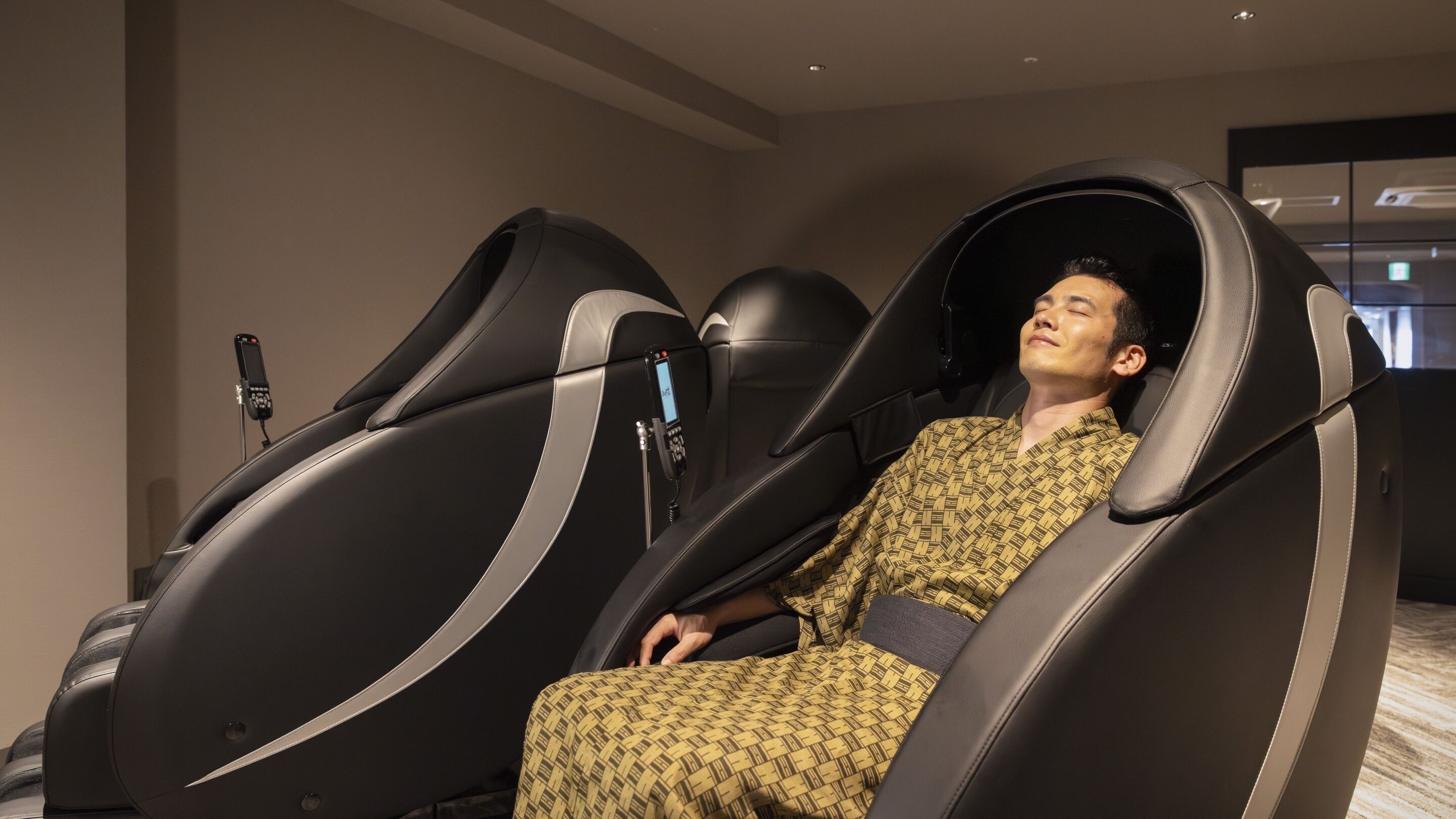A person in a massage chair with a phone attached to the headrest.