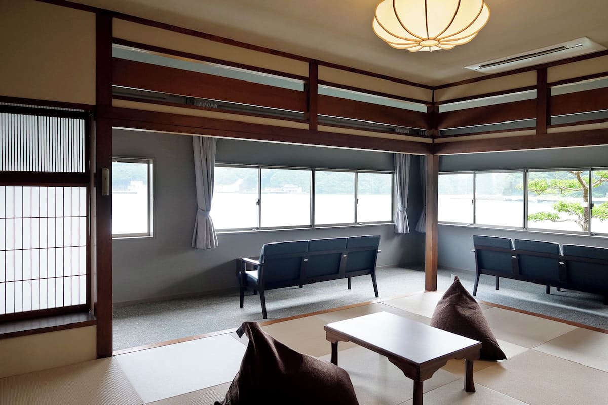 Una habitación japonesa tradicional con suelo de tatami, una mesa baja y asientos.