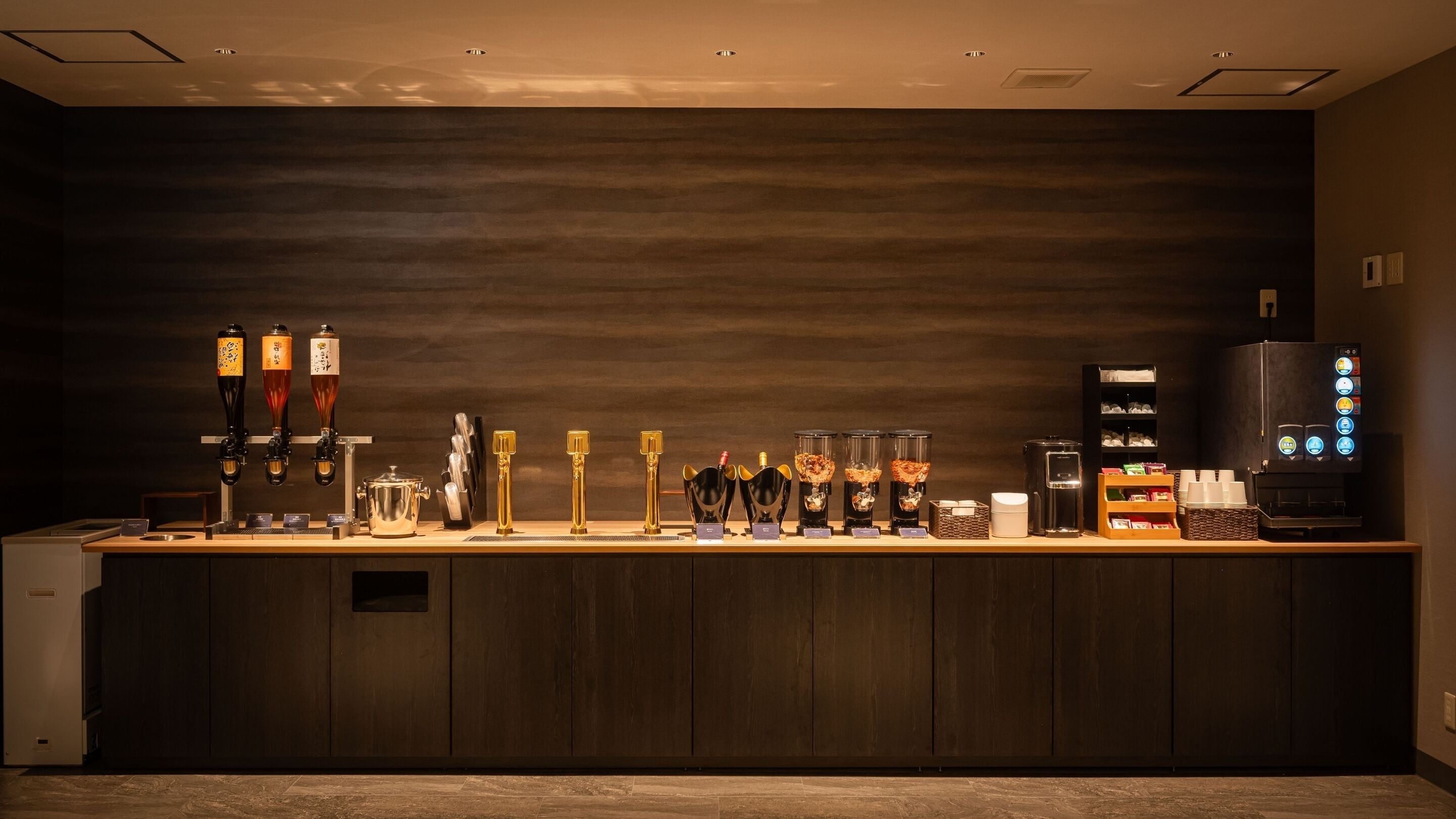 Uma área de bar com várias torneiras, uma máquina de café e uma seleção variada de garrafas.