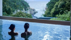 Dos personas en una piscina con vistas a la costa.