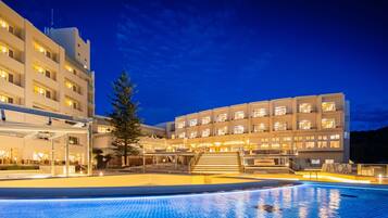 Un hotel con piscina, varios pisos y una fachada bien iluminada.