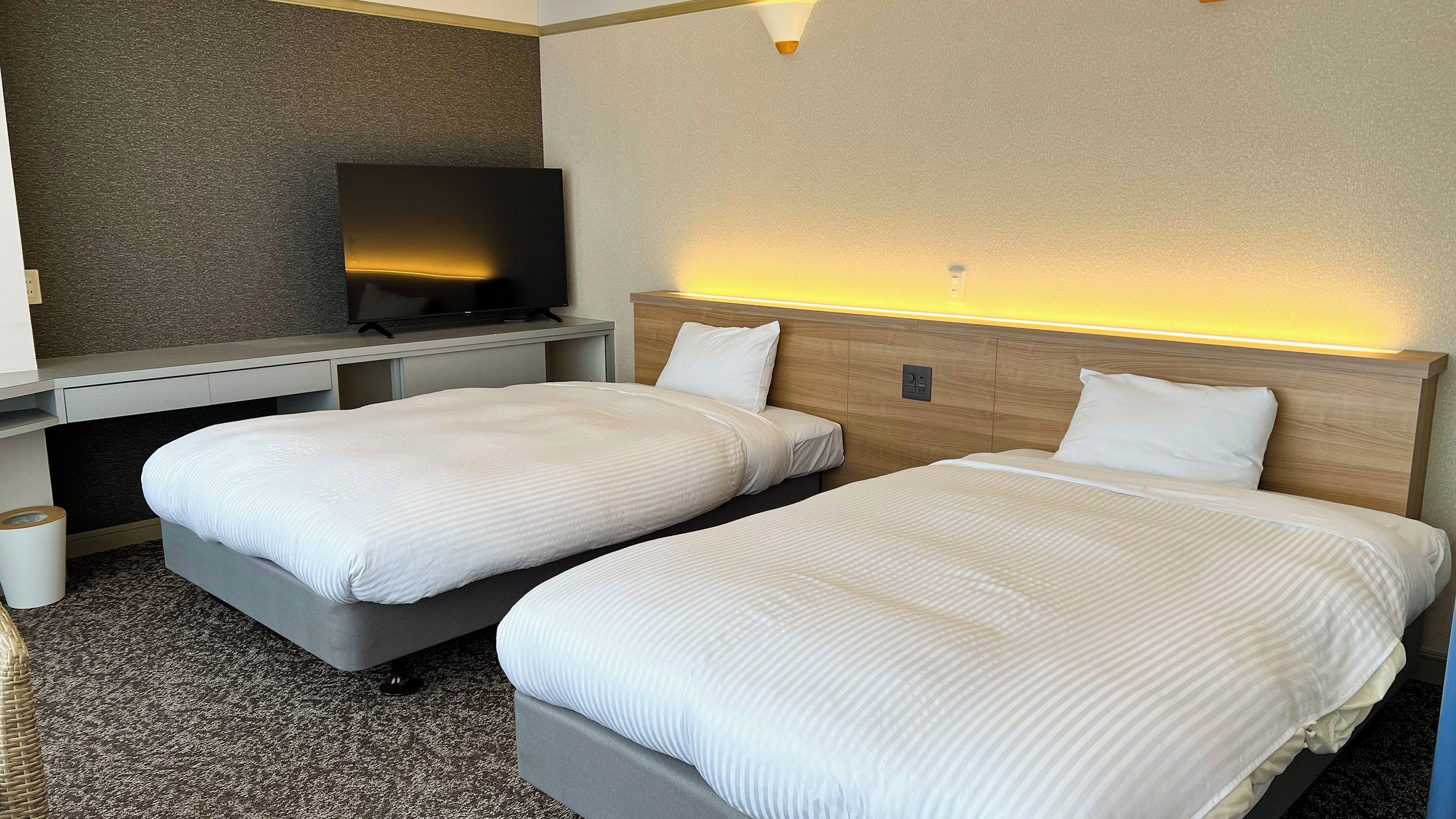 A hotel room with two beds, a TV, and a small desk.