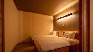 Habitación de hotel con cama, luz empotrada en la pared y cabecero de madera.