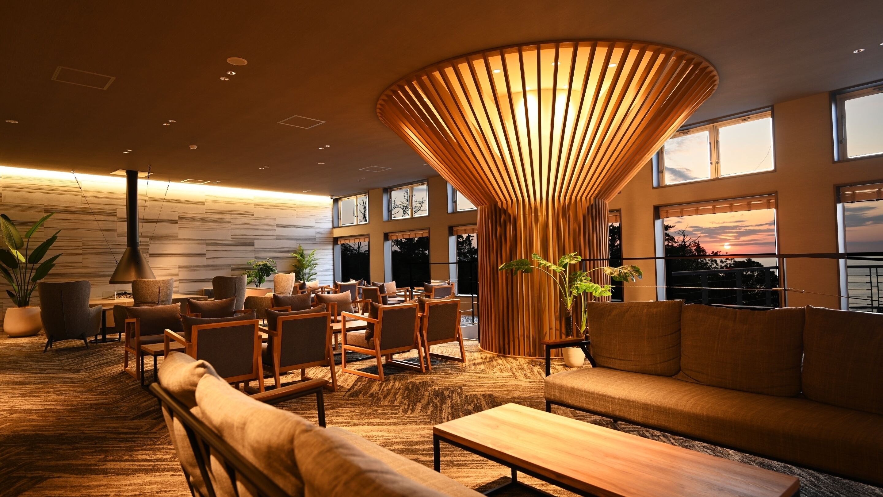 A modern interior with a central wooden structure, seating arrangements, and large windows.