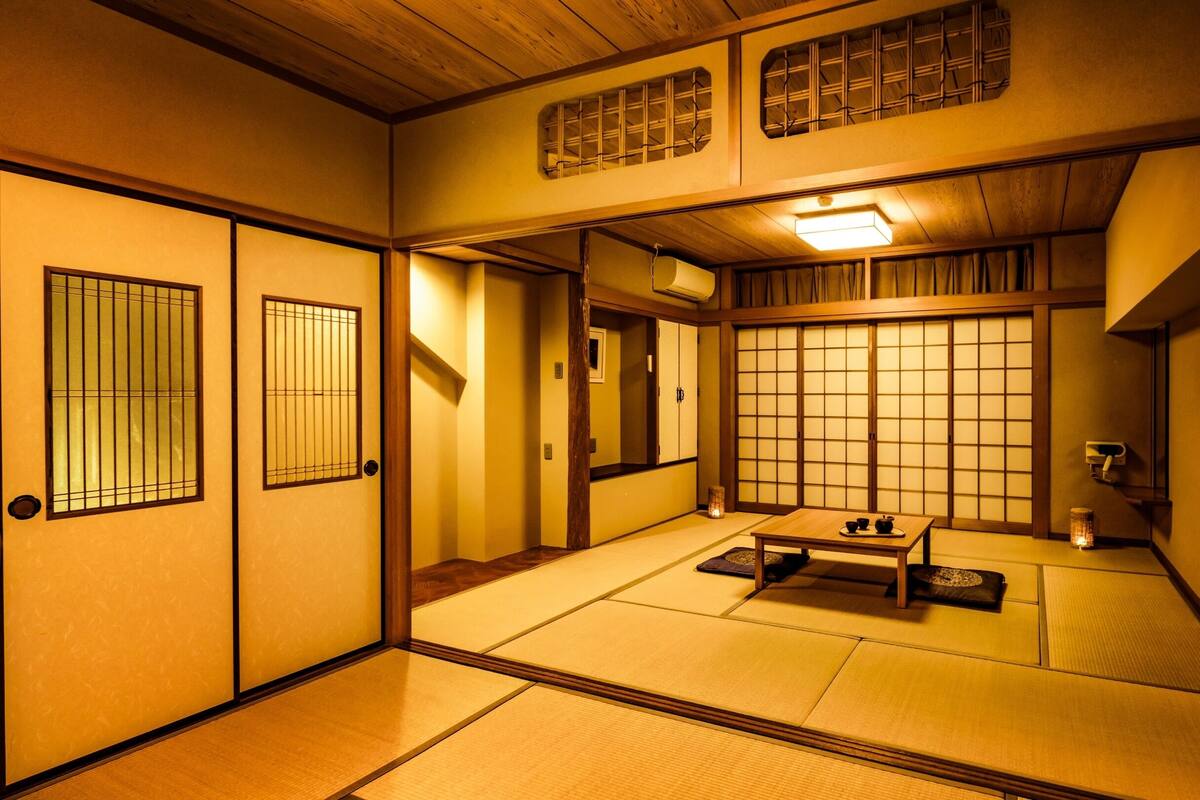 A traditional Japanese room with tatami flooring, sliding doors, and a low table with tea set.
