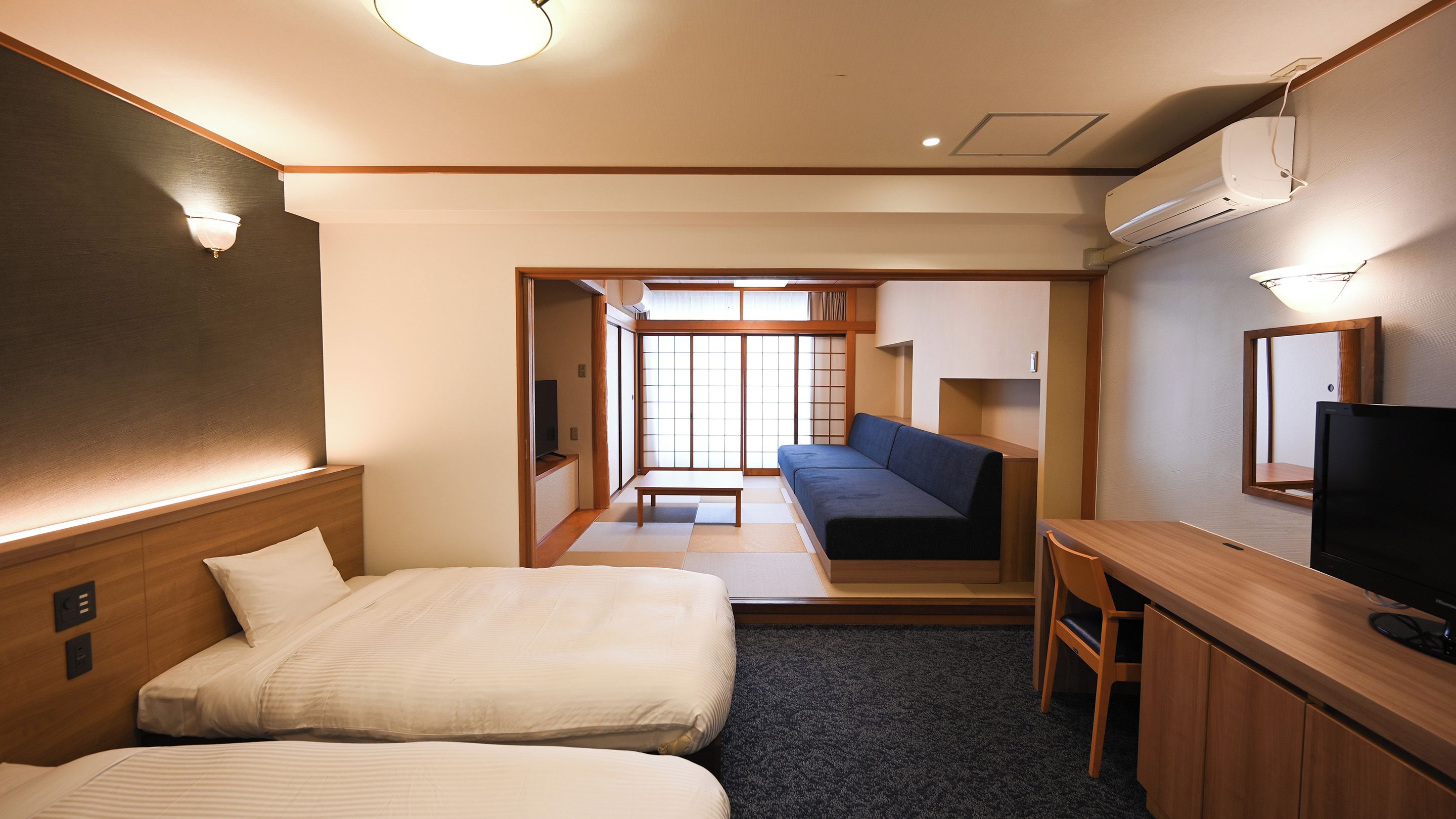 Habitación de hotel con dos camas, un sofá, un televisor y un escritorio.