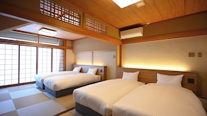 A hotel room with two beds, tatami mats, wooden beams, and a traditional Japanese-style ceiling.