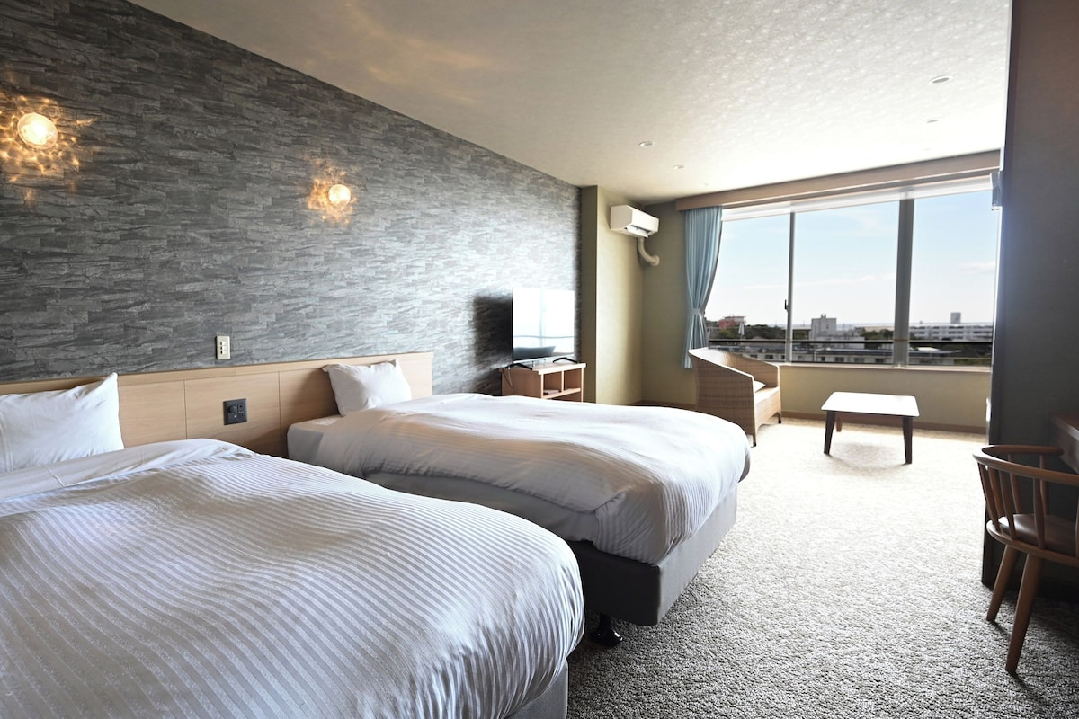 Une chambre d’hôtel avec deux lits, une télévision, un bureau et une vue sur la ville.