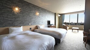 Una habitación de hotel con dos camas, televisión, escritorio y vistas a la ciudad.