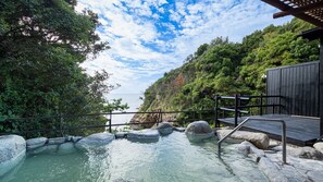 Une zone de sources chaudes dotée d’une terrasse en bois, de rives rocheuses et offrant une vue sur la mer.