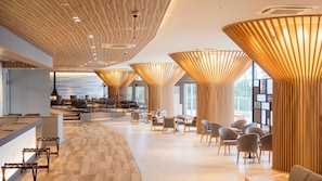 Un intérieur moderne avec un comptoir d’accueil incurvé, un espace salon et de grandes fenêtres.