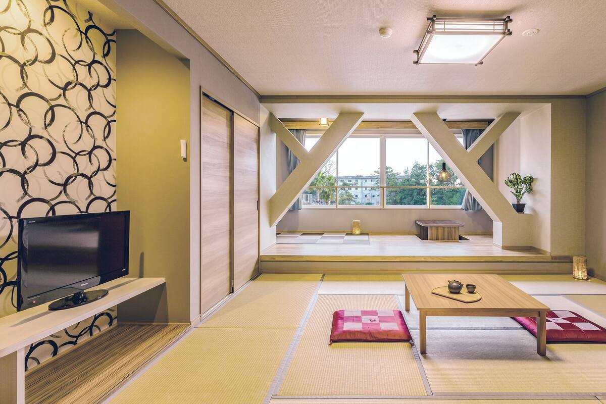 A modern living room with tatami mats, a television, and a view of the outdoors.