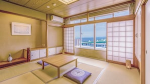 A traditional Japanese room with tatami flooring, a low wooden table, a cushioned bench, and a large shoji screen door.
