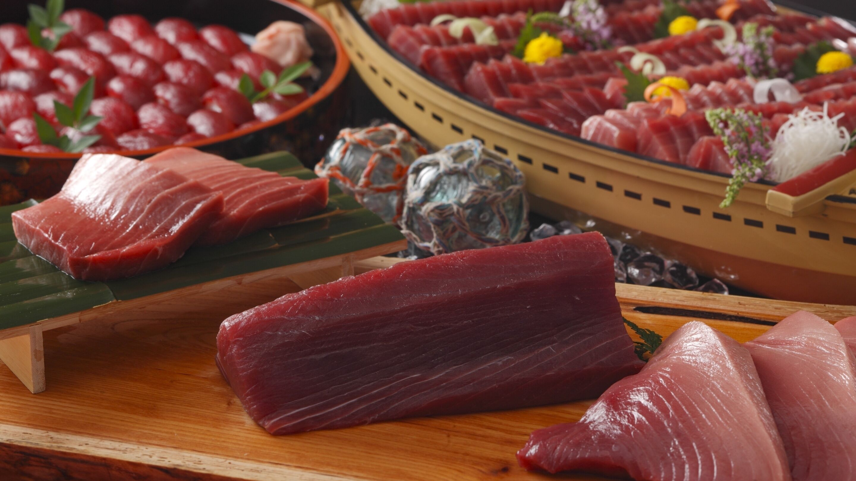 A variety of raw fish on wooden boards, likely for sushi preparation.