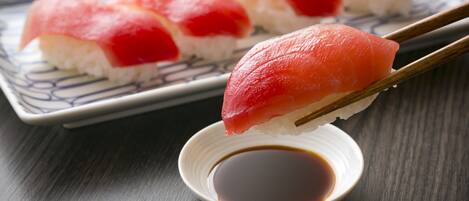 Des sushis présentés sur une assiette, accompagnés de baguettes et d’un petit bol de sauce soja.