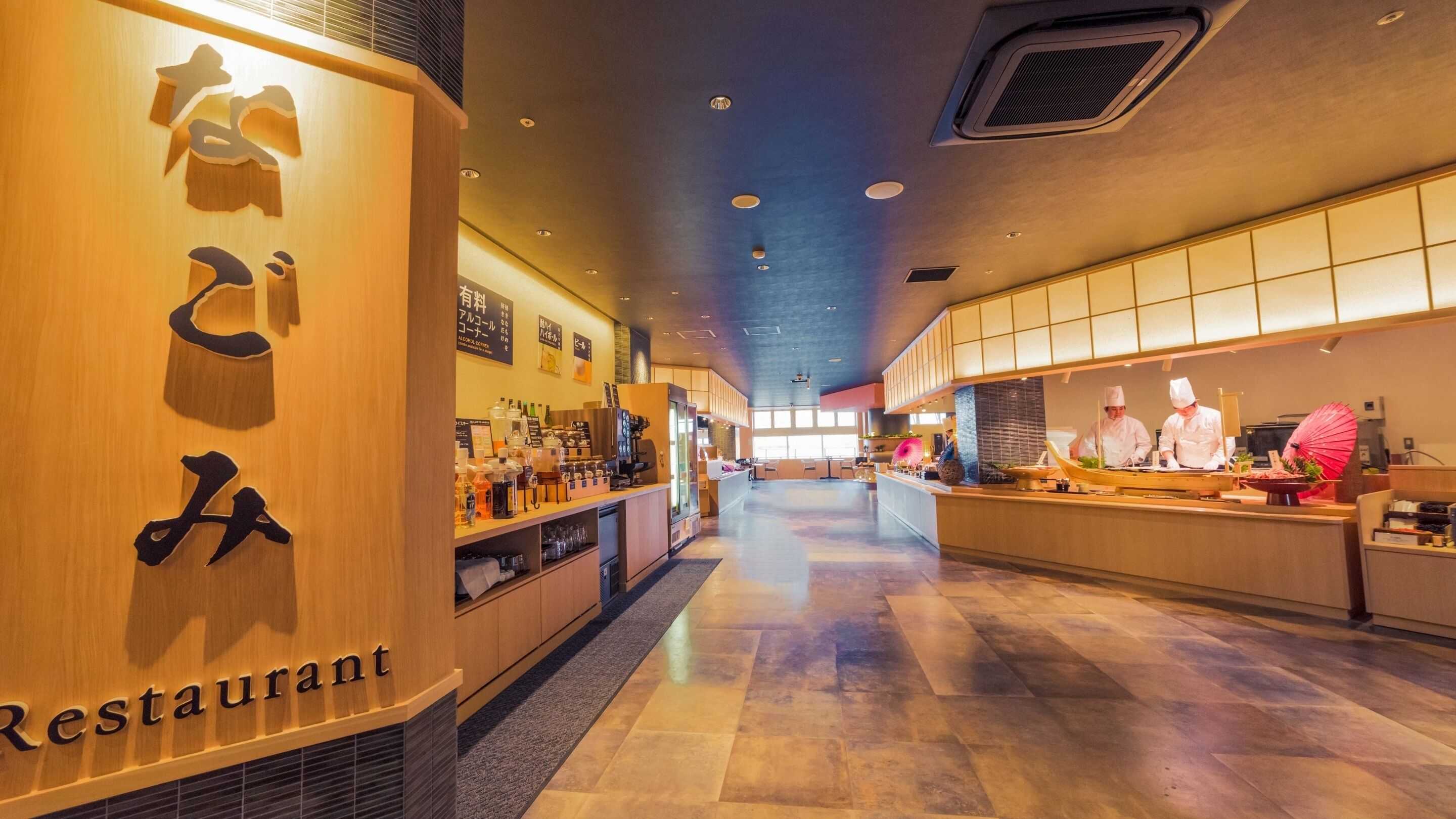 A restaurant interior with a wooden reception desk, a counter with a chef, and a tiled floor.