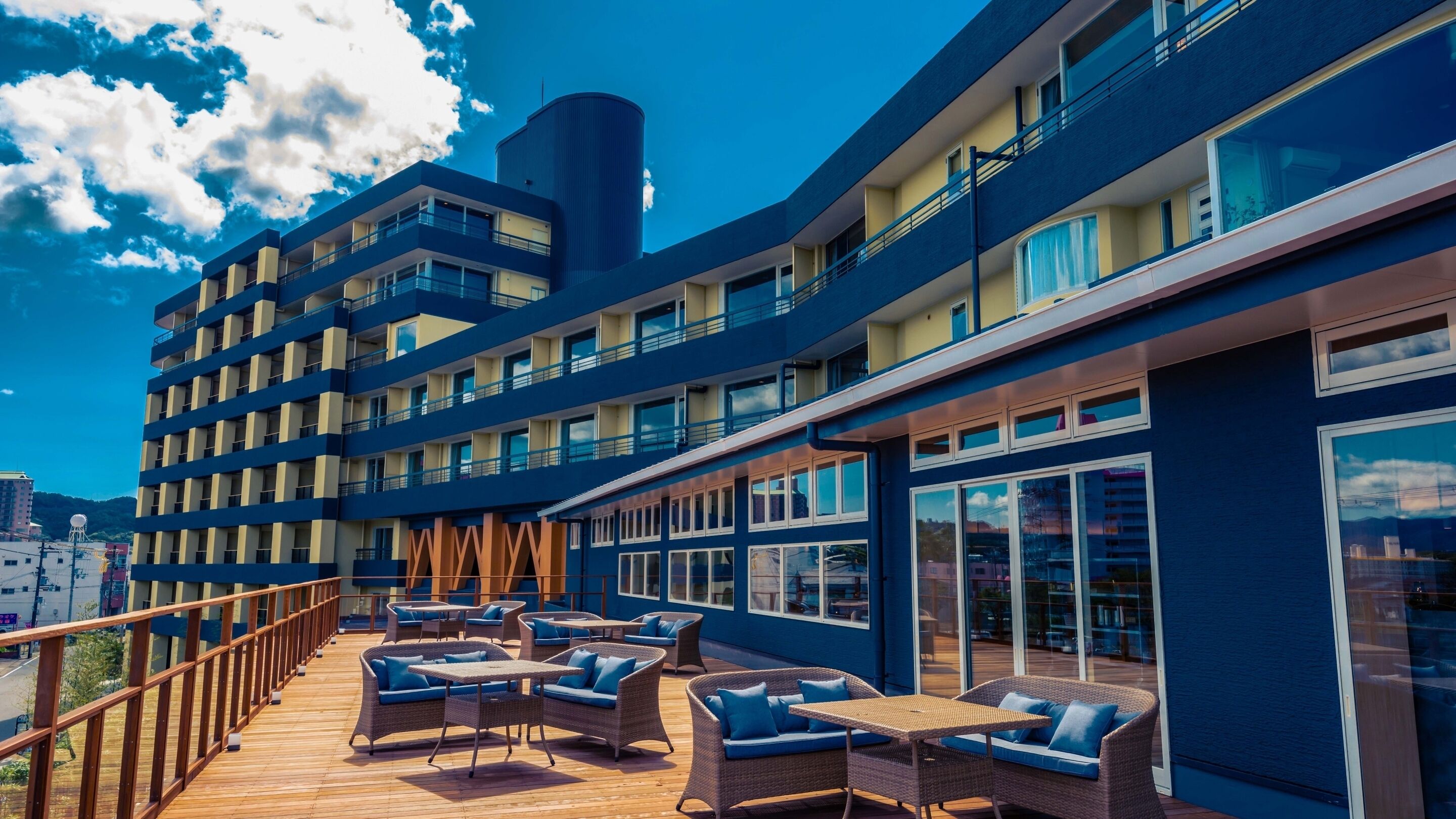 Un hôtel à plusieurs étages doté d’une terrasse et de grandes fenêtres.