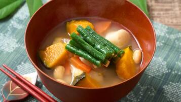 A bowl of soup with vegetables and tofu, accompanied by chopsticks and a decorative item.