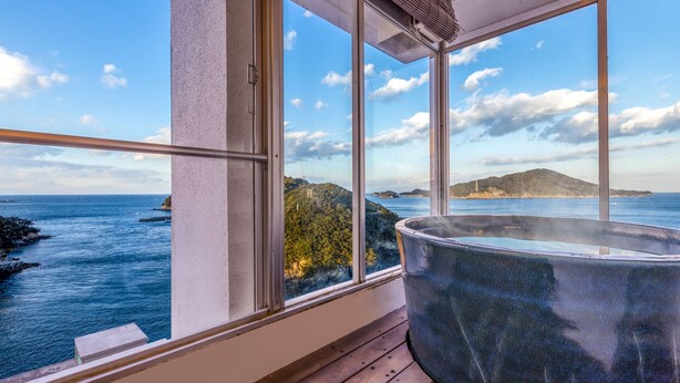 Un jacuzzi sur un balcon avec vue sur la mer et une île au loin.