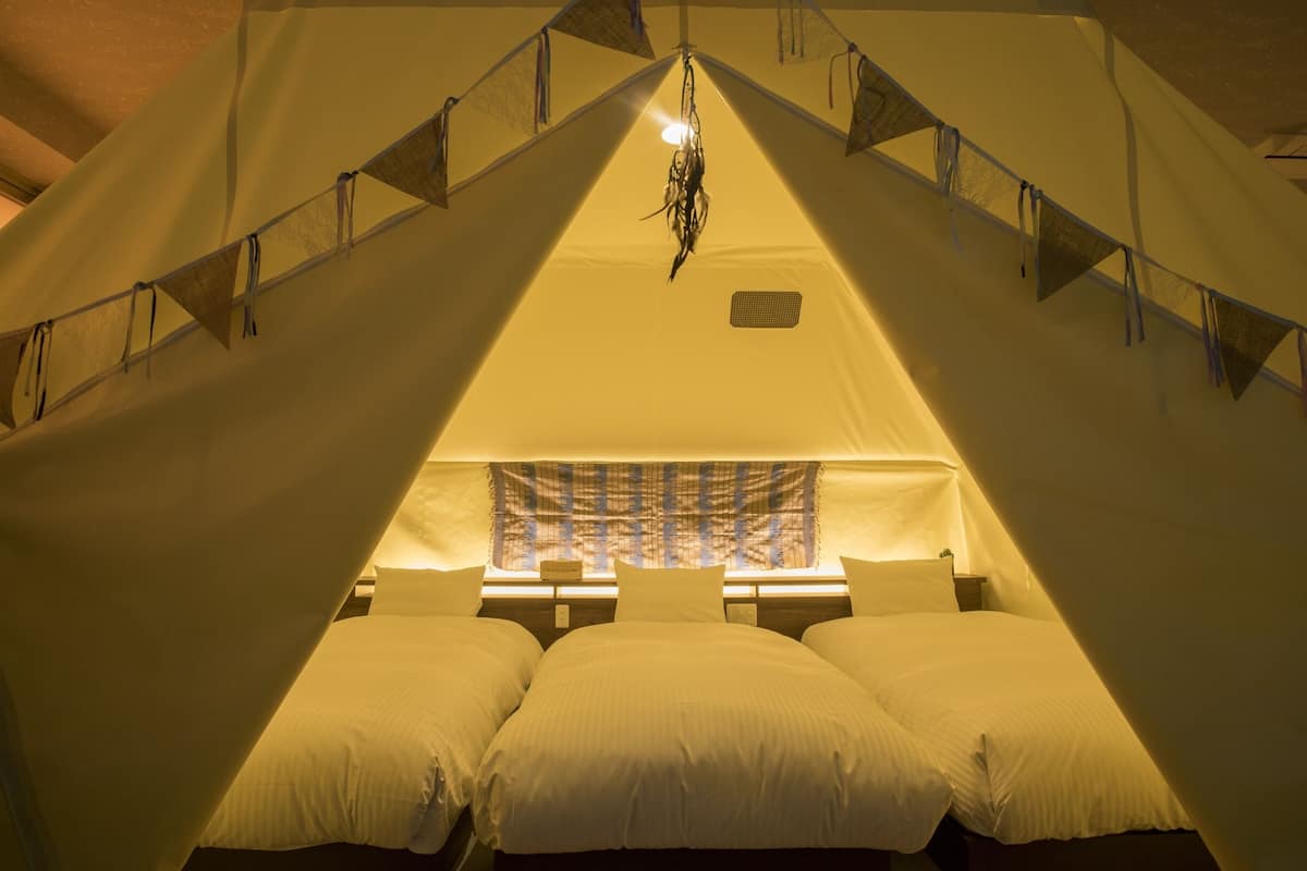 Ein Zelten mit einem Bett, einer Hängelampe und einem Fenster mit Vorhängen.