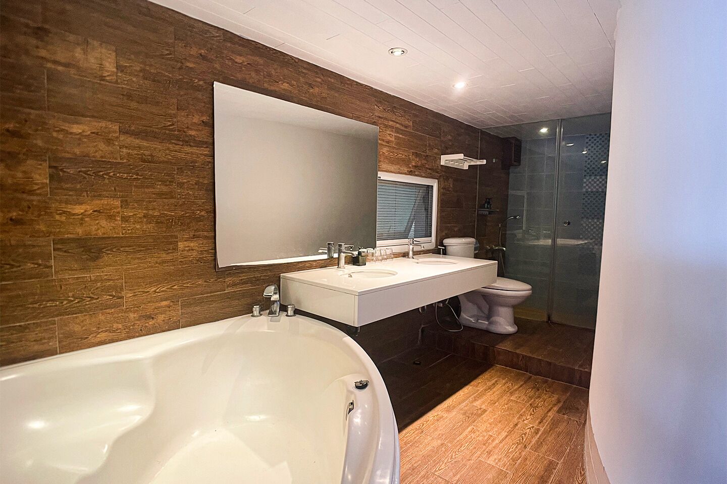 A modern bathroom with a large bathtub, a vanity with a mirror, a toilet, and a glass shower enclosure.