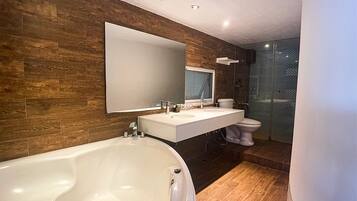 A modern bathroom with a large bathtub, a vanity with a mirror, a toilet, and a glass shower enclosure.