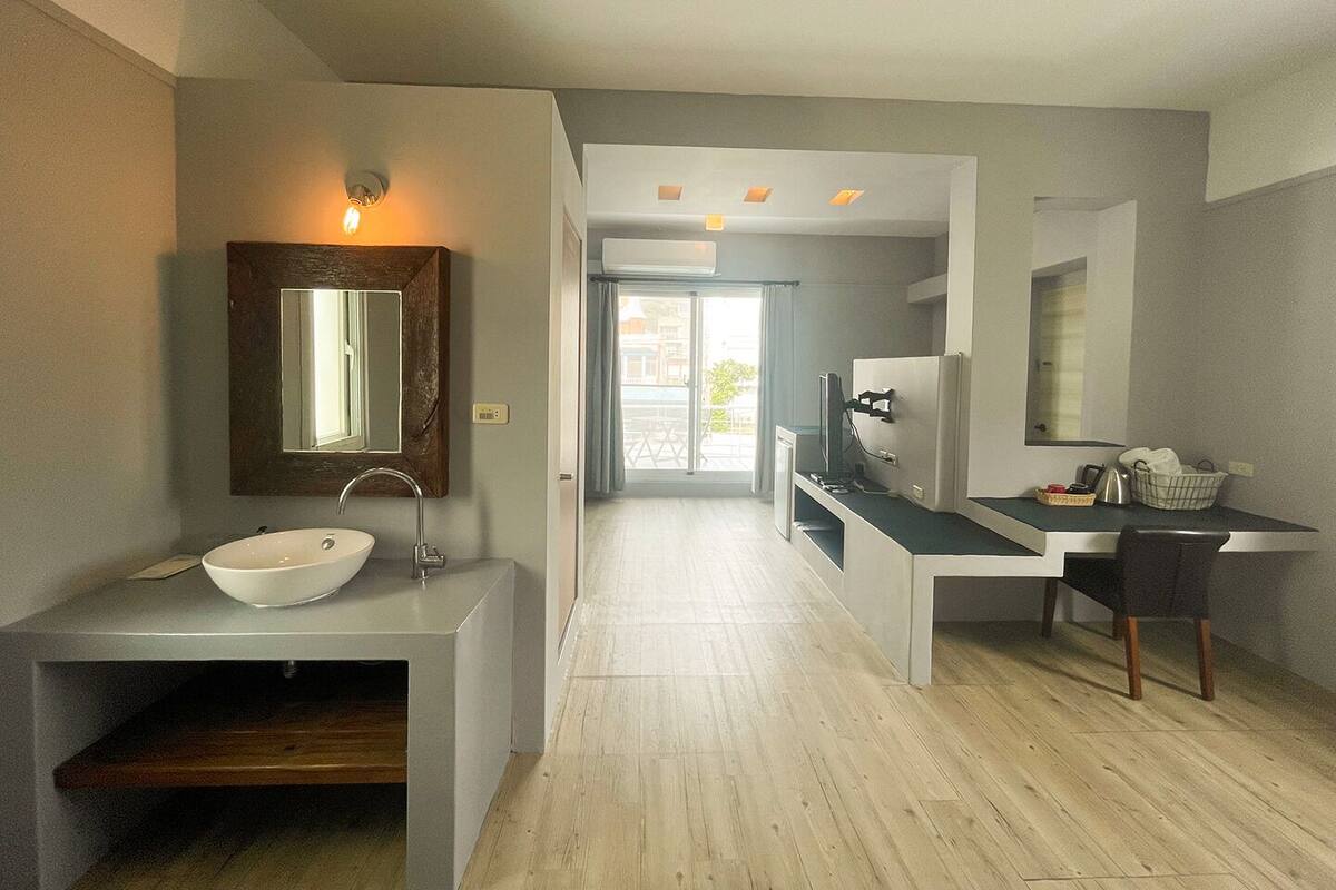 Ein modernes Badezimmer mit einem großen Spiegel, einem weißen Waschbecken und einer Holzausstattung. Im Hintergrund ist eine Dusche erkennbar.