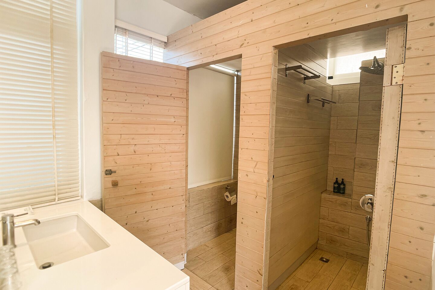 A bathroom with wooden paneling, a shower, and a sink.