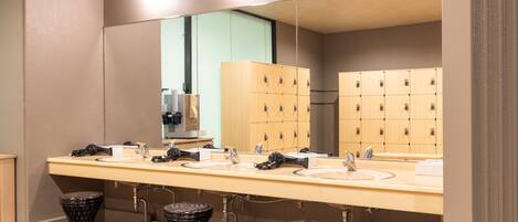 A public restroom with multiple sinks, a large mirror, and wooden lockers.