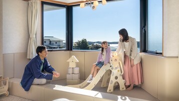 A room with large windows, a sofa, a play area with a slide, and a lamp.