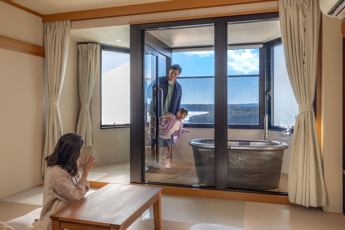 Ein modernes Zimmer mit einer großen Schiebeglasdoor zum Balkon mit Meerblick.