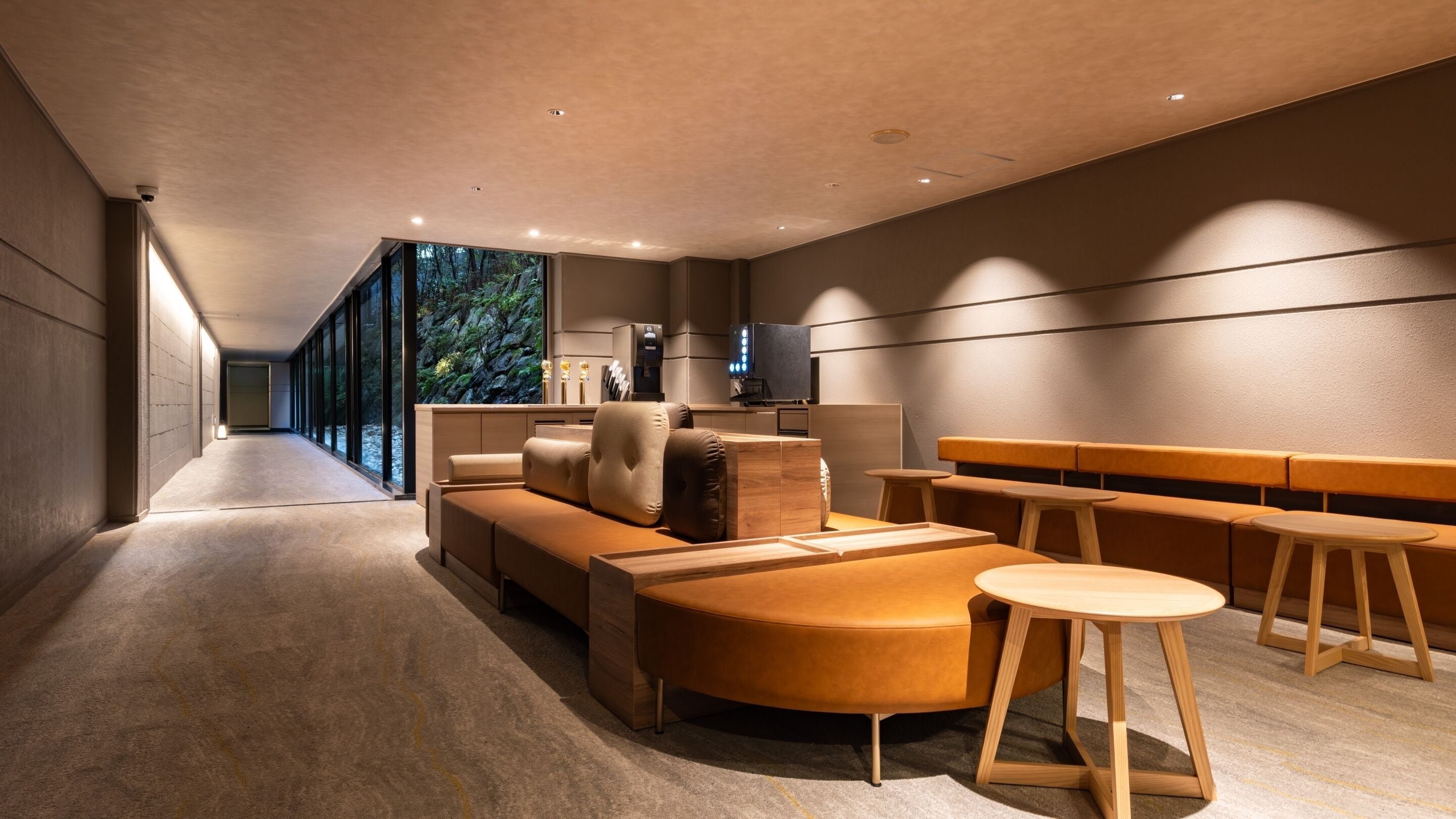 A modern interior with a sofa, ottoman, and bar stools.