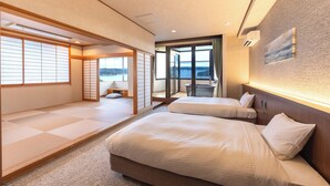 A hotel room with tatami flooring, two beds, a sliding door leading to a balcony, and a view of the sea. - Ooedo Onsen Monogatari Premium Shima Saichoraku (Shima)