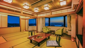 A traditional Japanese-style room with tatami flooring, a low table with a tea set, and a view of the sea at dusk. - Ooedo Onsen Monogatari Premium Shima Saichoraku (Shima)
