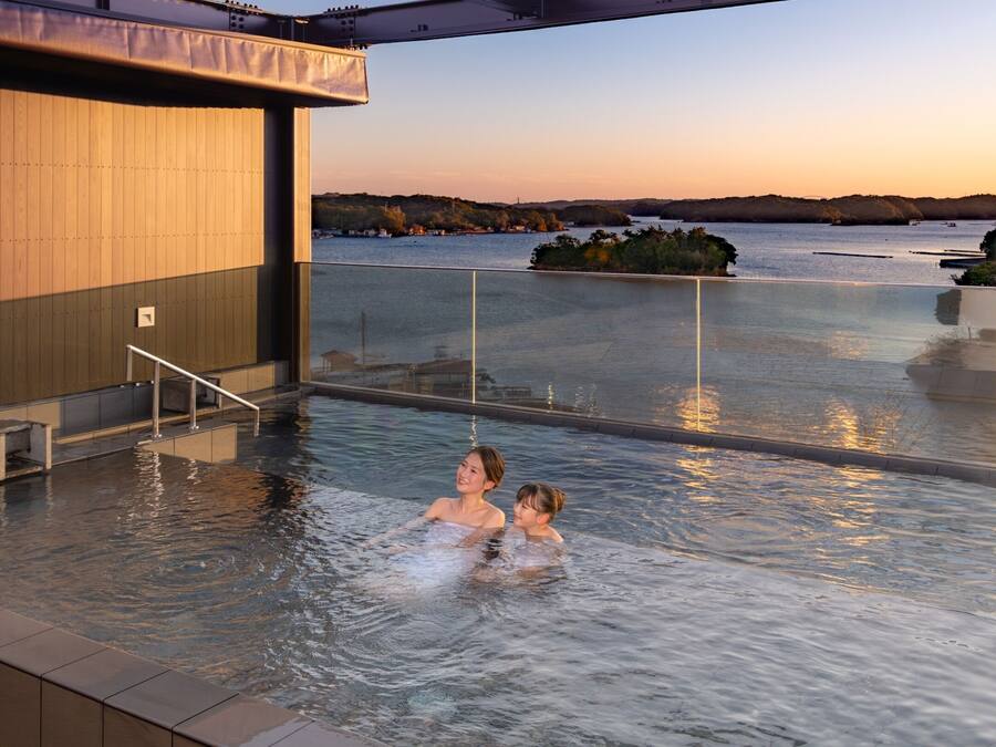 An indoor swimming pool with a view of a body of water and hills in the background.