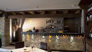 Un restaurante con barra de pared de piedra, chimenea de piedra y una mesa preparada para cenar.