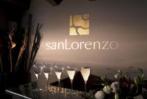 Uma área de bar com o logotipo 'sanLorenzo' e cinco copos de vinho branco no balcão.