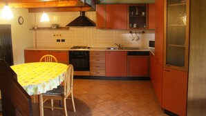 A compact kitchen with a dining table, chairs, a stove, and cabinets. - La Casa del Borgo (Brissago-Valtravaglia)