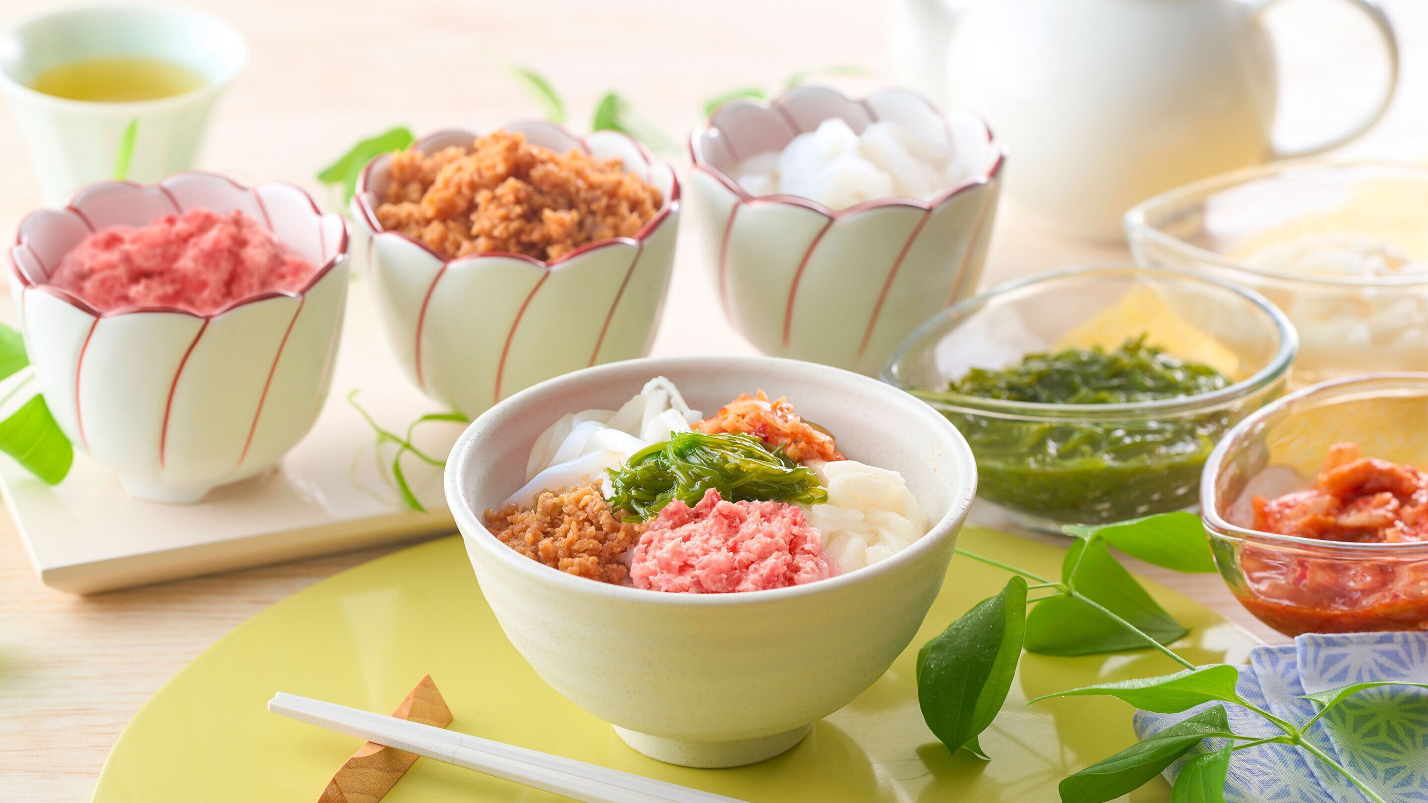 A bowl of food with various toppings, accompanied by small cups and bowls containing different dishes.