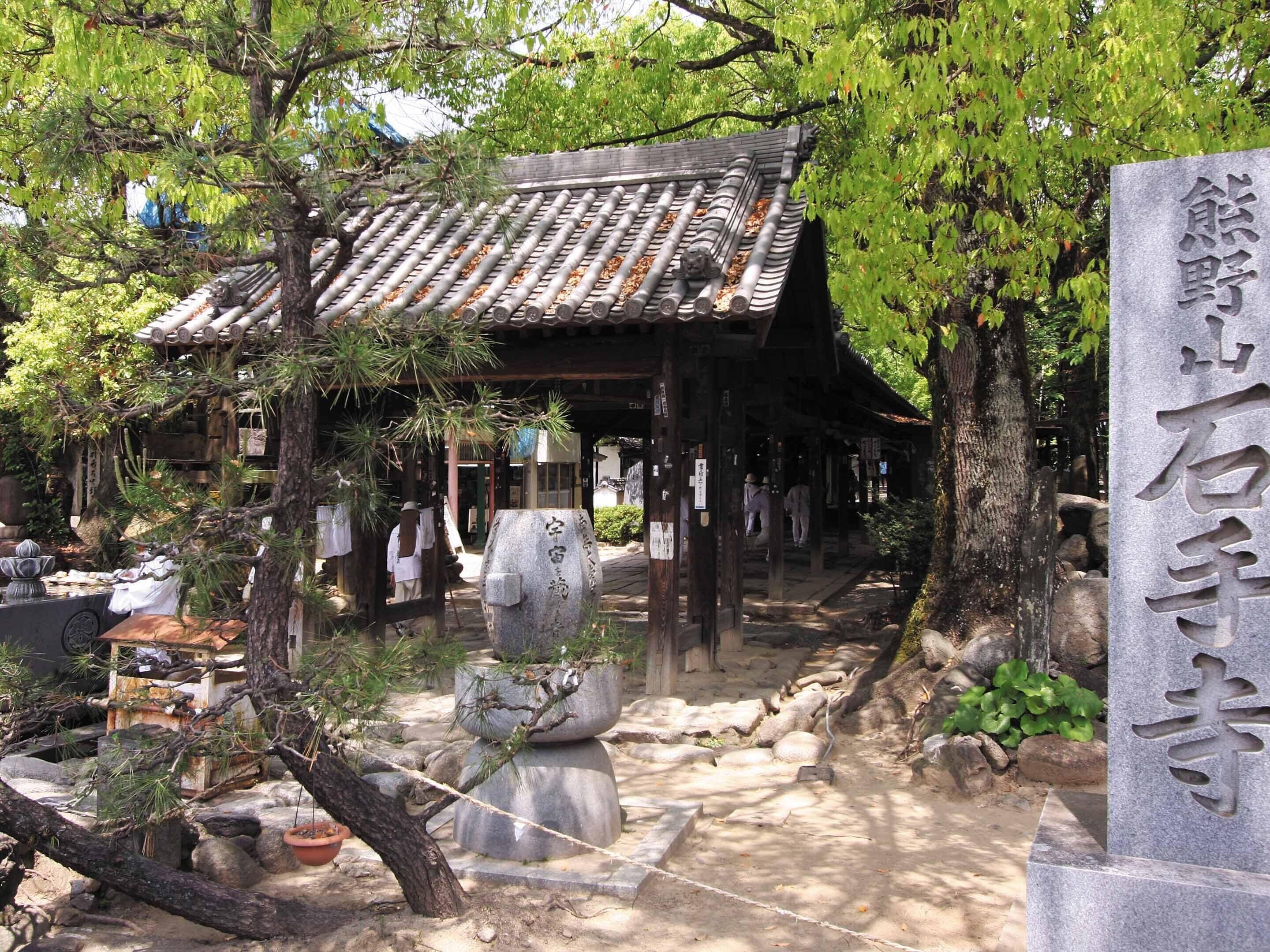 A traditional Japanese building with a tiled roof, surrounded by trees and stone lanterns.