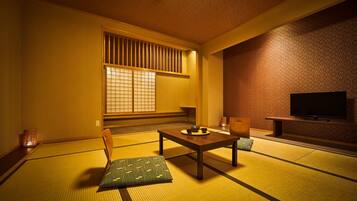 A traditional Japanese room with tatami flooring, a low table, a television, and a shoji screen.