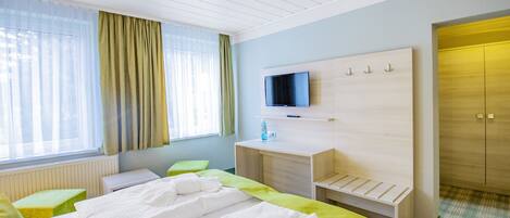 A hotel room with a bed, a desk, a TV, and a wardrobe.
